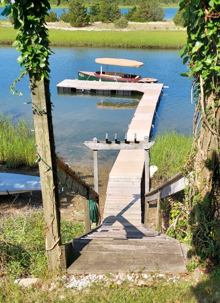 Image of an L shaped dock with a boat tied to the end. 