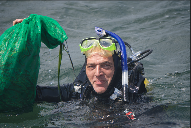Rob Vasiluth from the CCE Eelgrass Program holds up a bag of eelgrass seeds after the dive at Fisher’s Island. (Image: Emma DeLoughry)