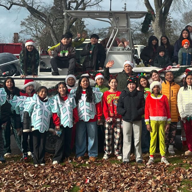 East Hampton Middle School Do Good, Be Good Club students standing in front of the Trustee Pump Out Boat for the 2025 Santa Parade. Students are dressed in holiday costumes and Santa Hats and are joined by their teacher David Cataletto, also a Trustee.